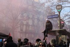 A man sits on the roof of a bus stop during protests in eastern Paris.