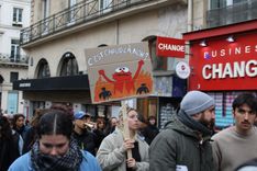 A protester holding a sign saying "It's getting a bit much, isn't it?"